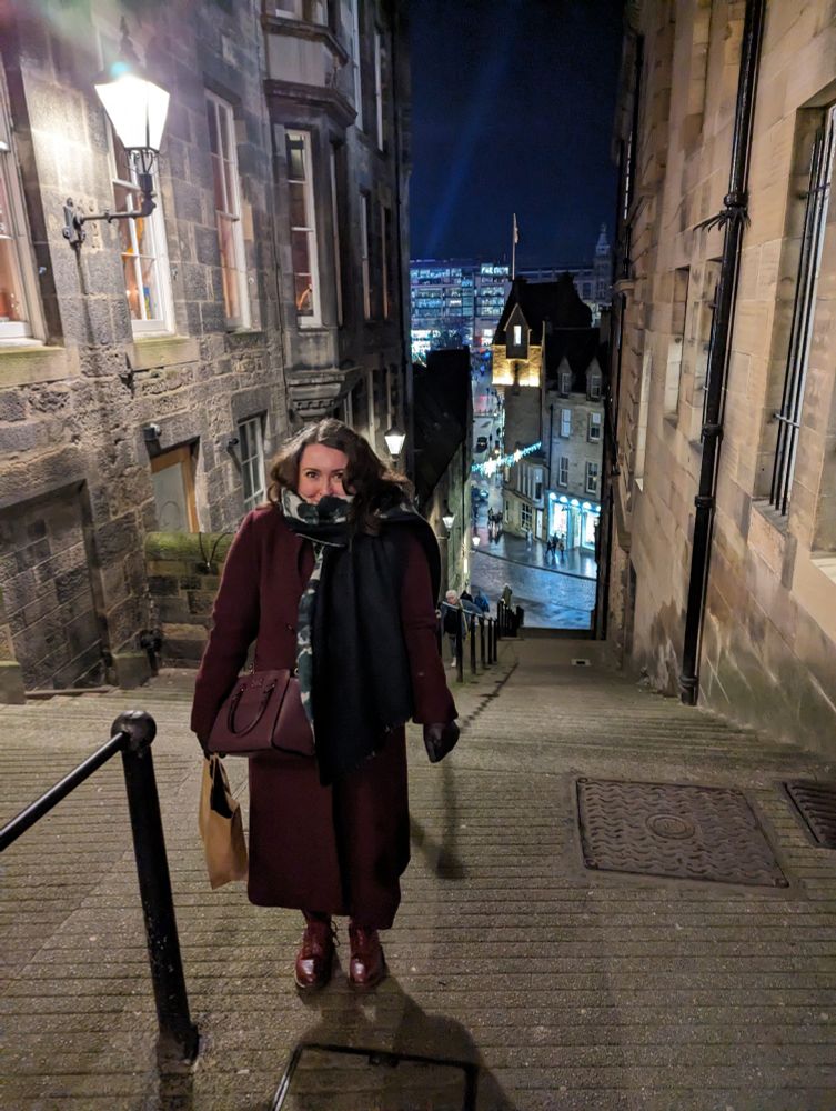 Woman in a purple coat stood partway down some steps in Edinburgh 