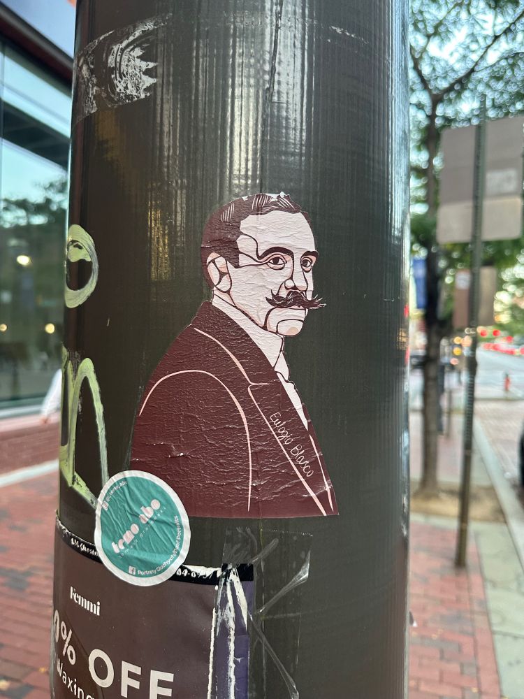 Sticker of a man with a handlebar mustache in a suit on a pole in Philadelphia