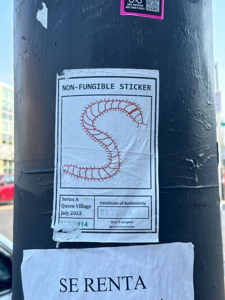 A white rectangle sticker that says “non-fungible sticker” with a crude drawing of a centipede. It kind of resembles a Pokémon card