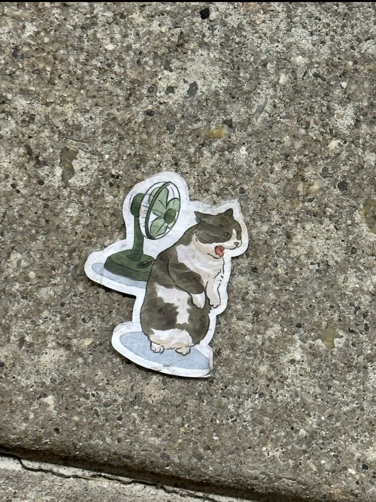 Another sticker of a cat in front of a retro fan with a very upset expression. Does not like the blow. Also located on the ground.
