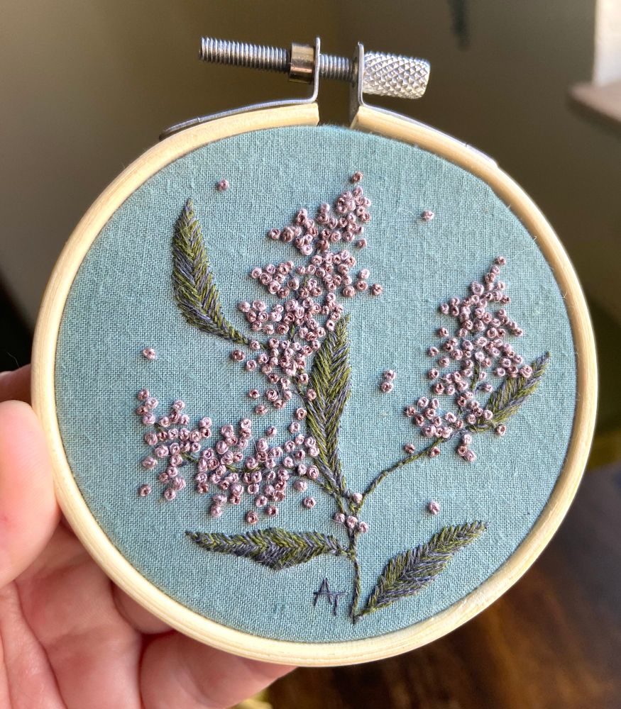 an embroidered depiction of purple heather flowers on a muted turquoise background, available in my etsy shop. 
