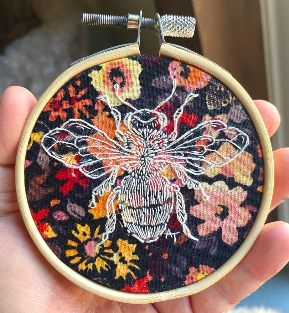 embroidery piece depicting a honey bee on a wildflower background 