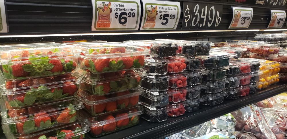 A packed-full display of berries at the supermarket, including the labels above them showing the prices.  One sticker reads "Classy Mixed Berries."  The berries are, in fact, very classy.