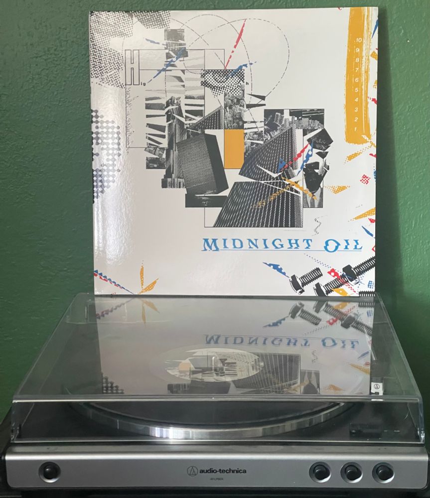 Midnight Oil “10, 9, 8, 7, 6, 5, 4, 3, 2, 1” perched atop a turntable. The cover is a scattering of urban images across a white field.