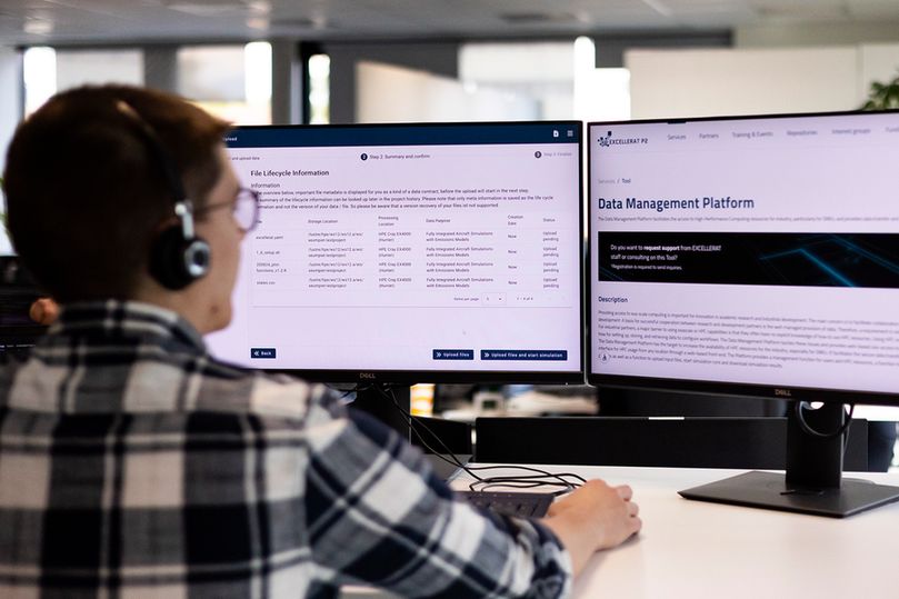 SSC-Services staff sitting in front of two screens, one showing the Data Management Platform on the EXCELLERAT Service Portal.
