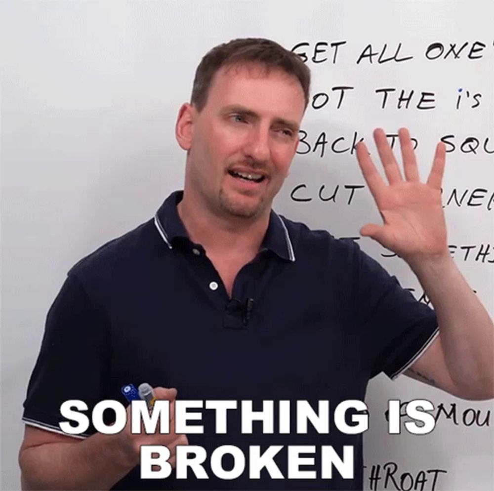 a man stands in front of a white board with something is broken written on it