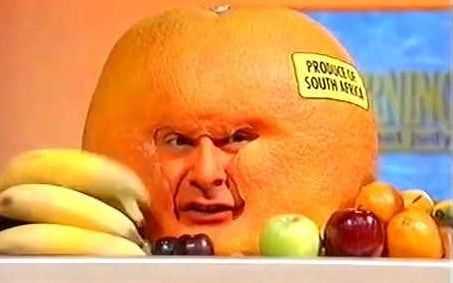 The Curious Orange from "This Morning with Richard Not Judy." A giant orange with a man's face and a "Produce of South Africa" sticker, on a counter, next to a variety of other fruit. (IRL: an actor wearing an orange headpiece/ mask, with his body under the counter. Obviously.)