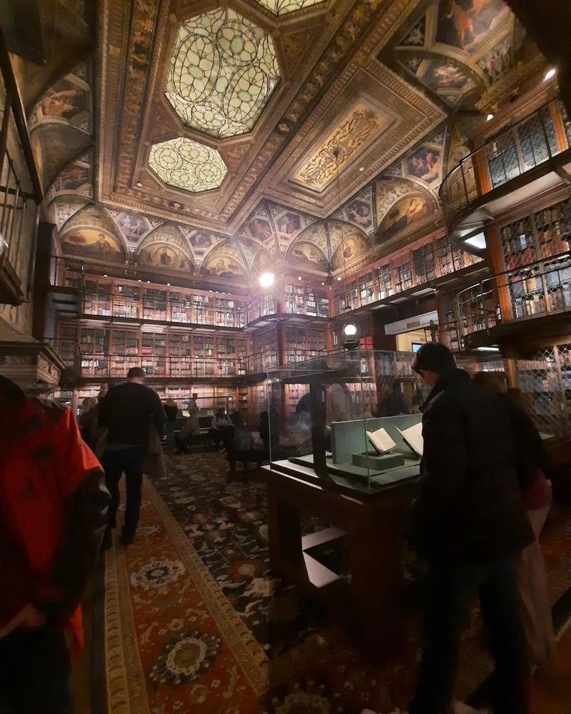 Wide angle shot of a ginormous room with a painted ceiling and shelves upon shelves of books on two levels. A large patterened carpet on the floor. One of those rooms you walk into and say, "Holy shit, look at this."