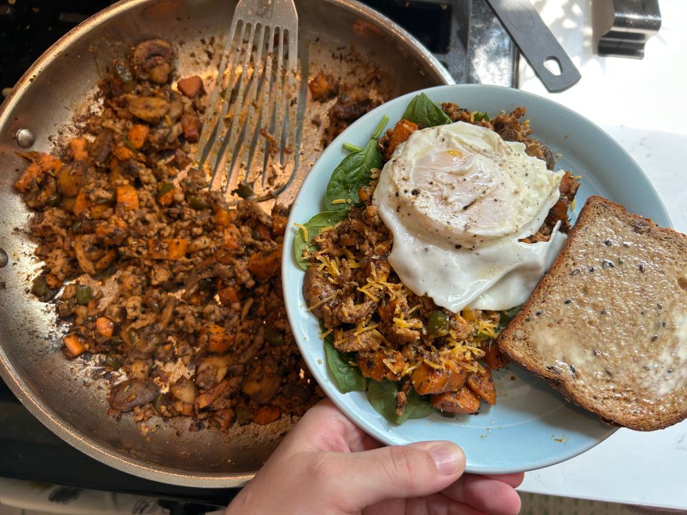 big pan of hash & a blue plate of hash over spinach w a fried egg & slice of buttered toast