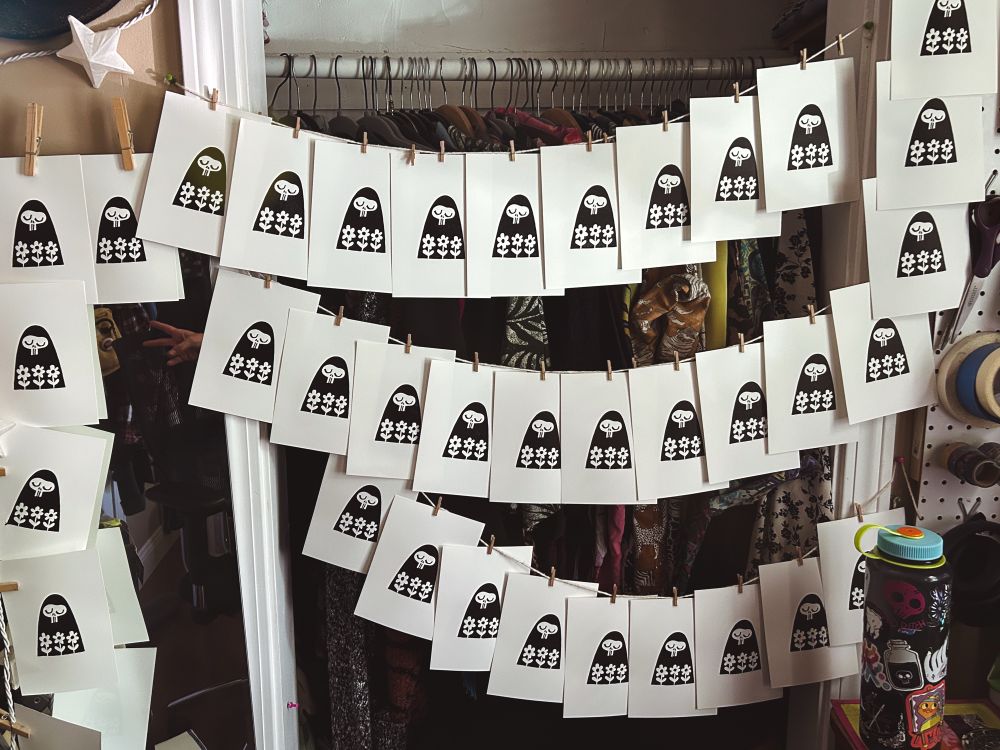 strings of the print described in the prior image hung up to dry over an open closet