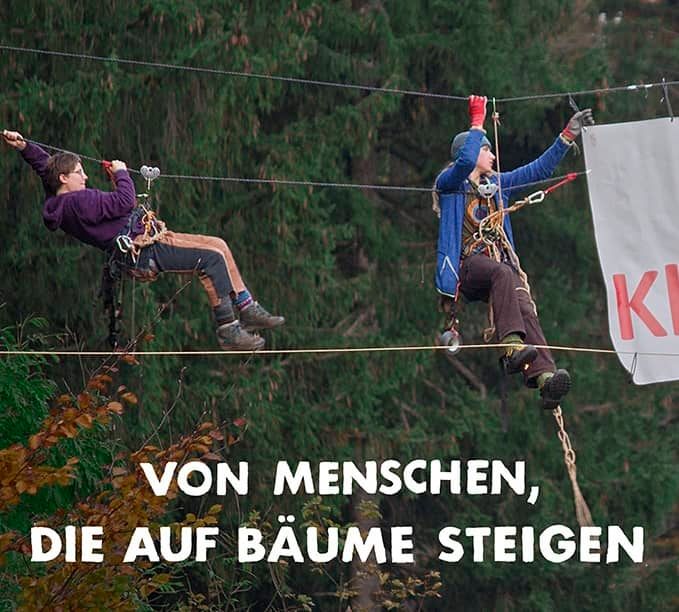 Film Plakat: von Menschen die auf Bäume steigen. Zeigt zwei junge Menschen, die mit einem Banner zwischen Bäumen hängen 