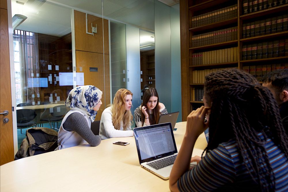 Five students sat around a desk in a group study room in Main Library