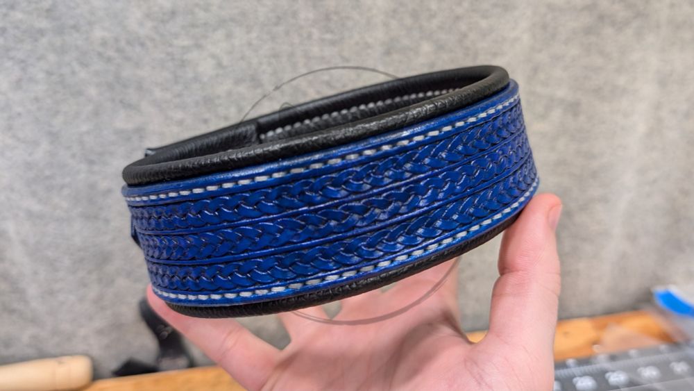 Blue and black leather collar. Blue main straps with three rows of braid stamptooling, black leather lining, silver-white thread, stainless steel hardware with colored rivets to match.