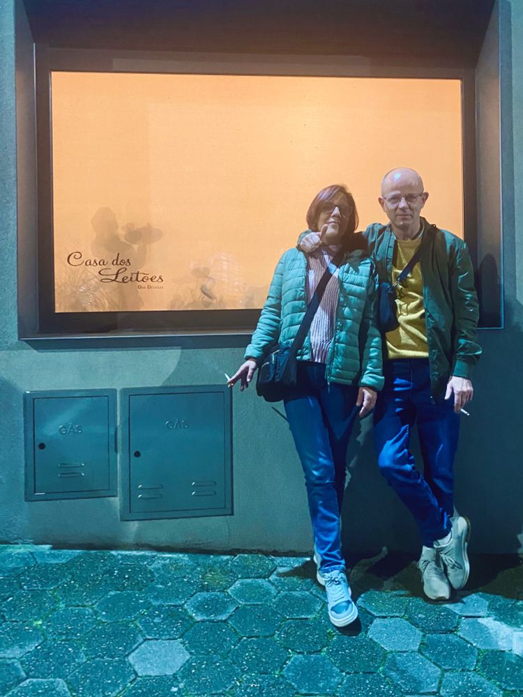 a nightshot of a couple leaning against a restaurant window