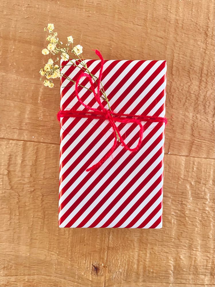 Um presente embrulhado em papel de fantasia vermelho e branco.