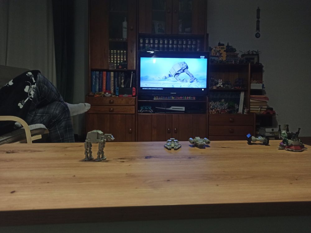 Un mini AT- AT mirando de reojo la batalla de Hoth y el momento en que un AT- AT gigante se desploma en la nieve