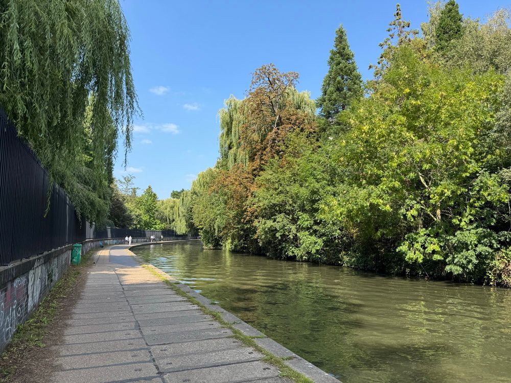 A photo of a canal with a towpath on the left bank and trees on the right 