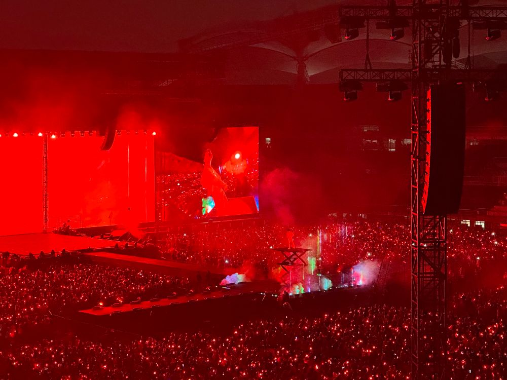 A shot of J-Hope on the Stage Final concert day 1 from the East side of Goyang stadium. The venue is glowing red with army bombs and he is dancing on an elevated part of the stage. 