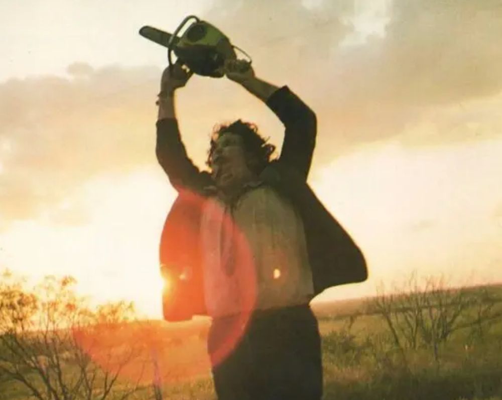 Leatherface swinging his(?) chainsaw in the dawn.
