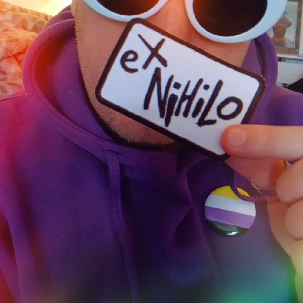 Orion from the band Scarlet Lashes holding up a denim patch that says 'Ex Nihilo' on it