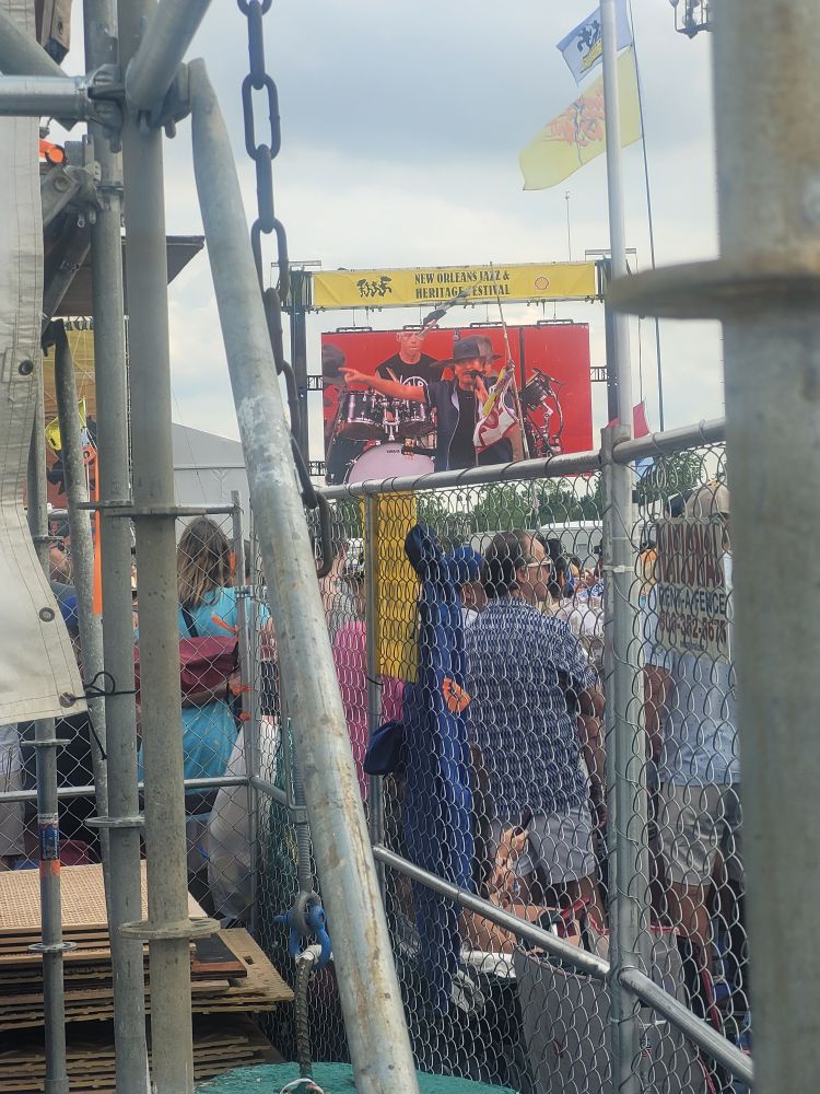 Peaking over a chain link fence, we see several different flags and a video board with Pearl Jam's Eddie Vedder on stage.