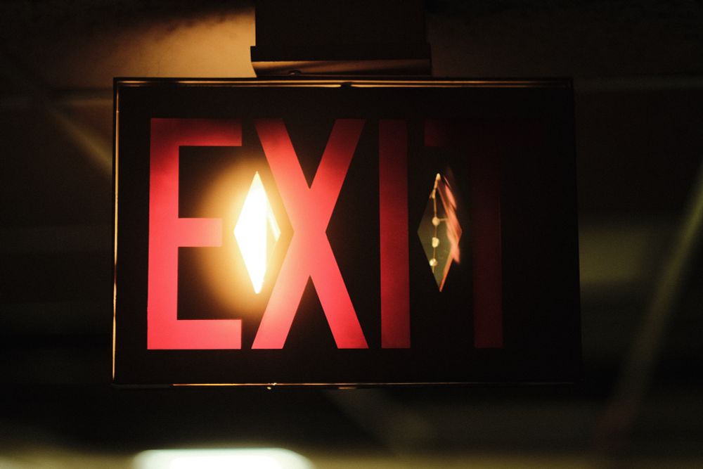 A photo of a broken exit sign, partially illuminated