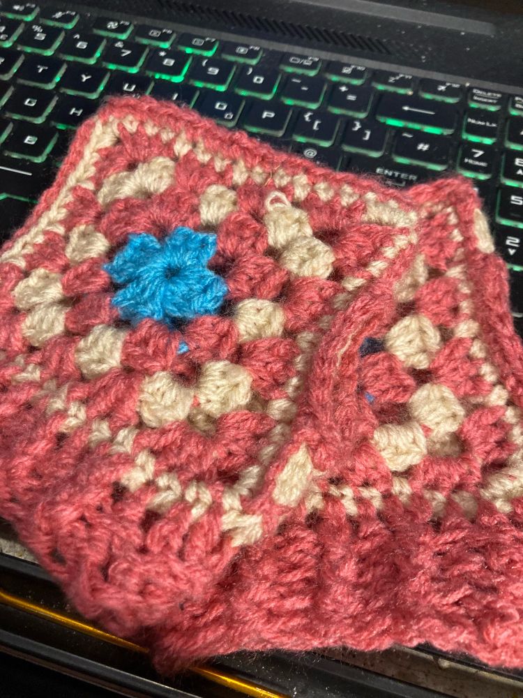 A pair of fingerless mittens made out of pink, cream and white granny squares 