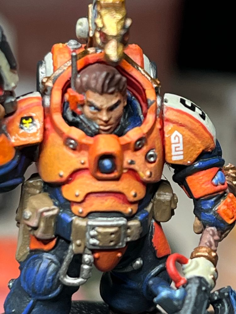Frontal image of Theyn of my Hearthkin Pioneer Kill Team. Model is painted in safety orange, black and dark blue. 
