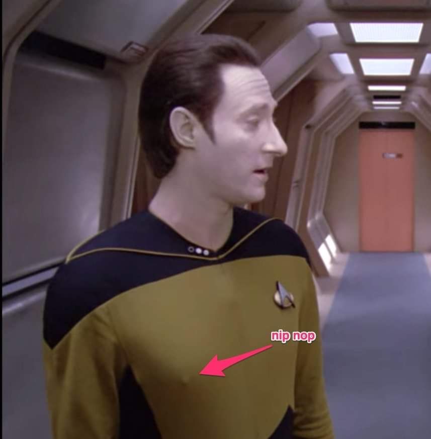 A screenshot of Data in the hallways of Enterprise-D with a pink arrow pointing to his nipple showing through his uniform that reads: "nip nop"