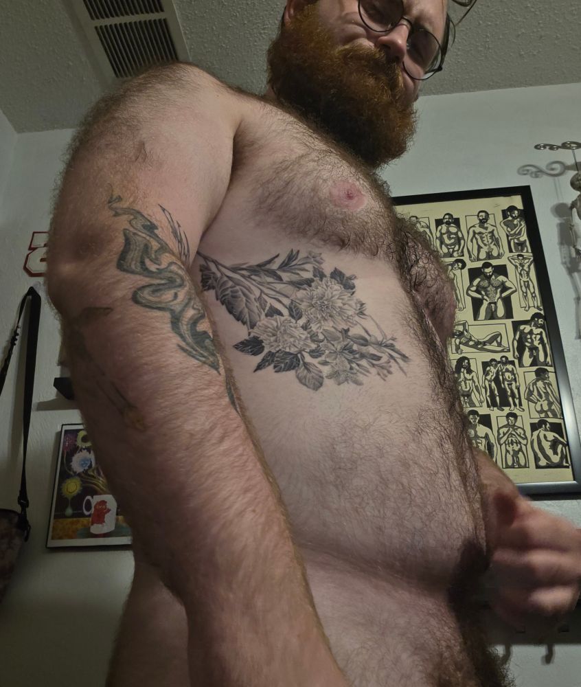 A photo of myself from a downward angle, mainly showcasing the flower bouquet tattoo I just got on my left rib, while also showing my chest popping out a but, a little bit of bush, and a concept of some cheeks.