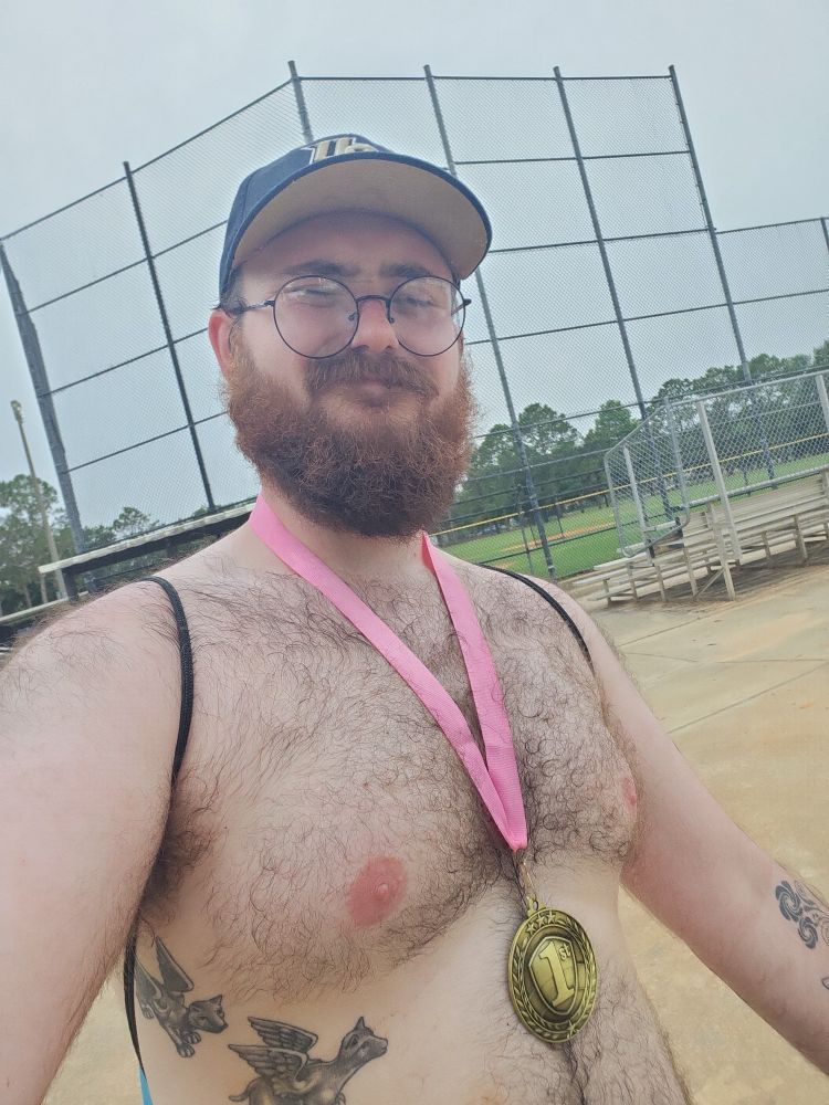 I'm standing shirtless with a 1st place medal around my neck, a kickball field behind me as it's starting to rain outside