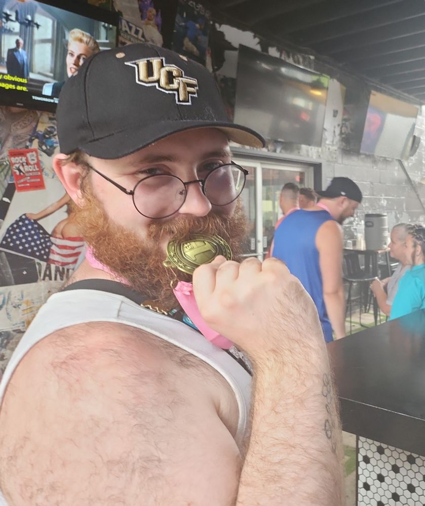 I'm holding the medal from the previous photo up to my mouth, looking at the camera. I now have a white tank top on