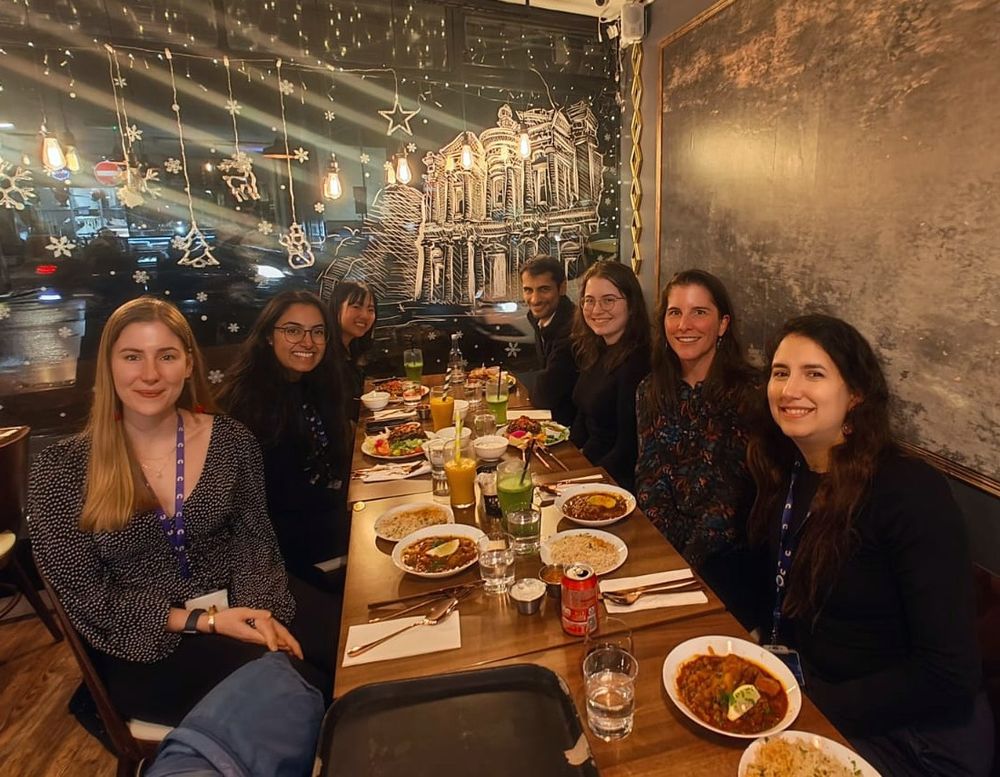 7 scientists sits around a table set with delicious food to celebrate.