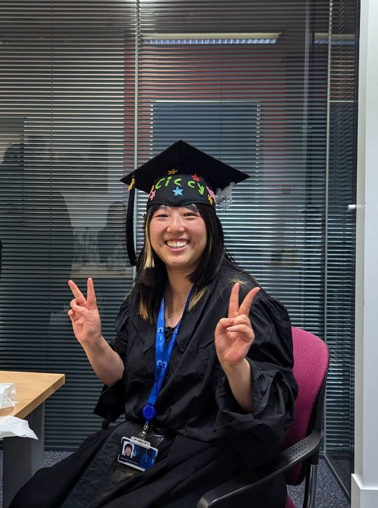A happy PhD graduate Ciccy Wang poses with a decorated graduate hat after passing her viva.