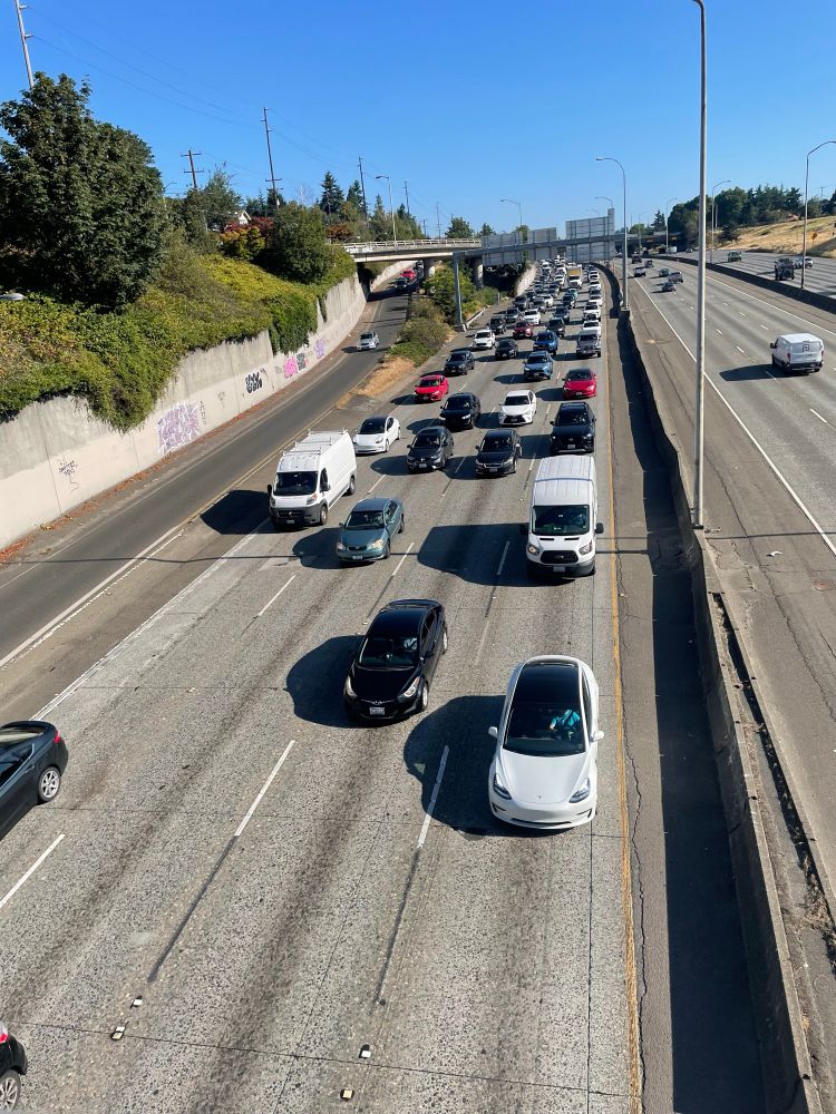 A highway with lots of people driving alone. Gray and desolate infrastructure 