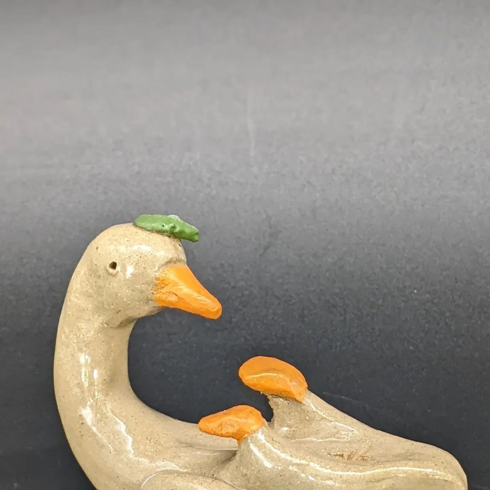 Little ceramic duck on his back with a tiny leaf on his head