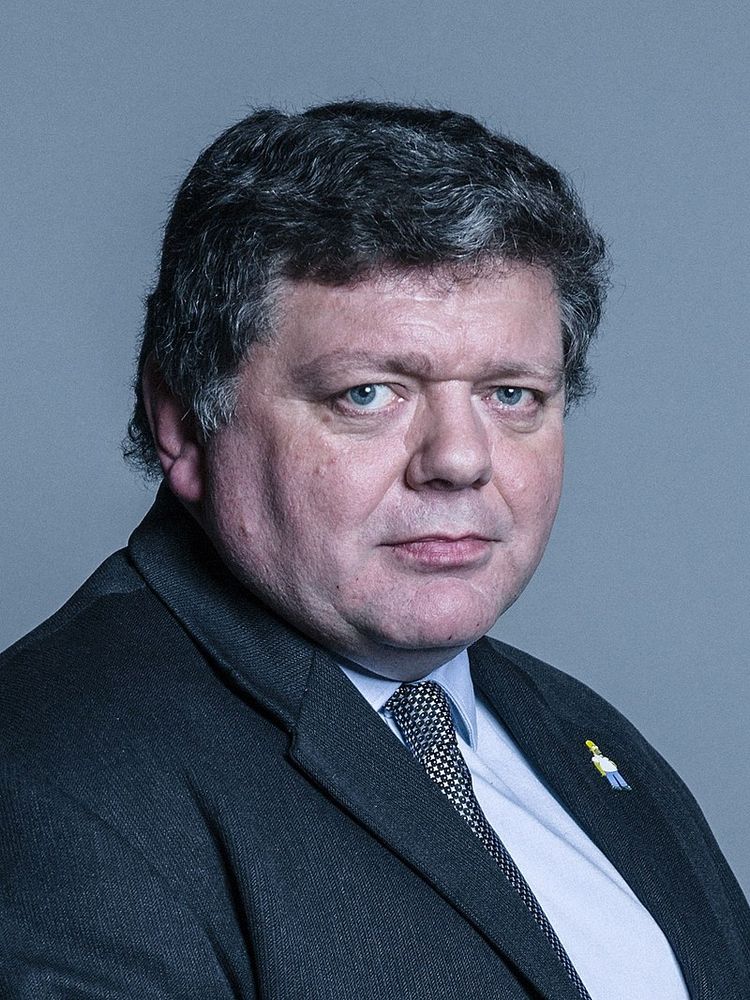Dominic Hubbard, 6th Baron Addington wearing a Homer Simpson pin