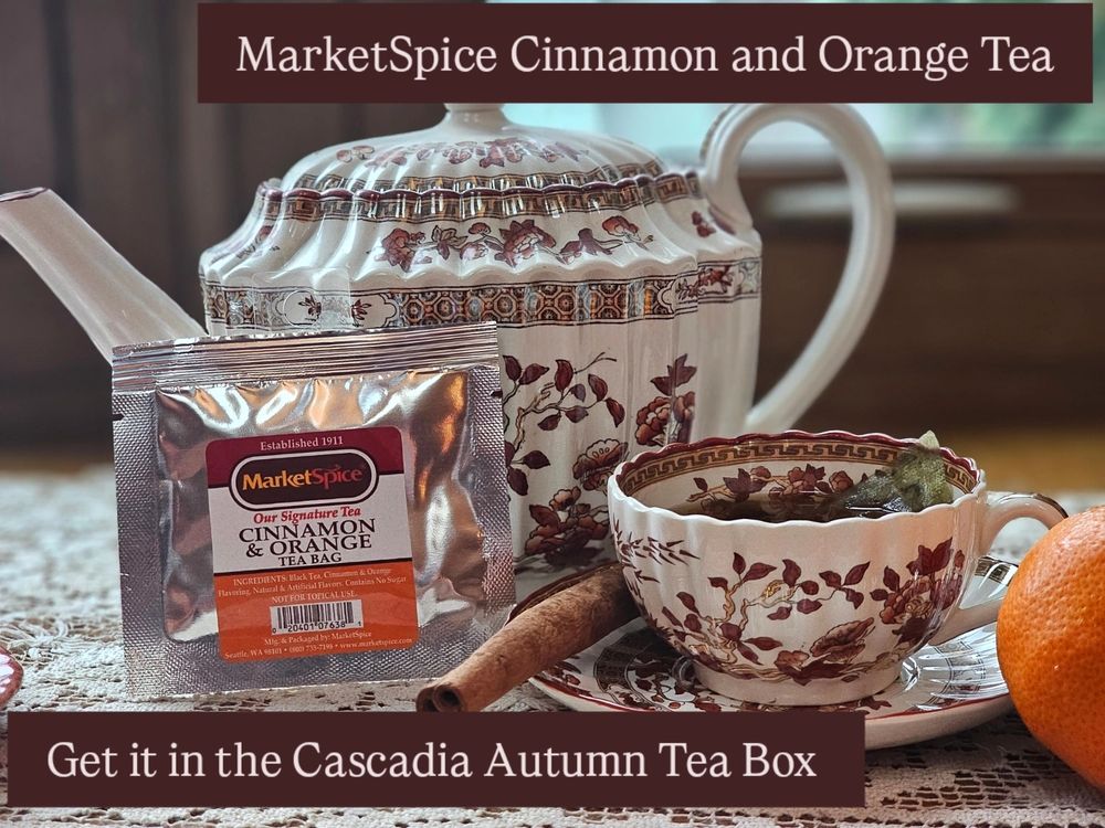 Spode India Tree teapot and cup with MarketSpice cinnamon and orange tea bag, a cinnamon stick, and an orange, sit in a windowsill. 