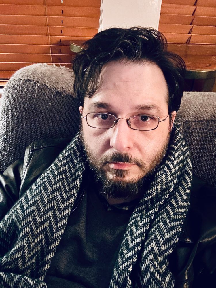 Selfie of an exhausted man lying near as flat as possible on an old sofa chair. 