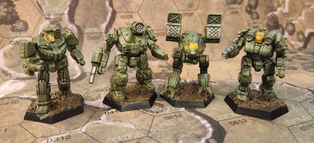 Four battlemechs painted in olive drab, with dark earthy bases, and yelloe/orange cockpits. From left to right: Wolverine, Thunderbolt, Catapult, Griffin.