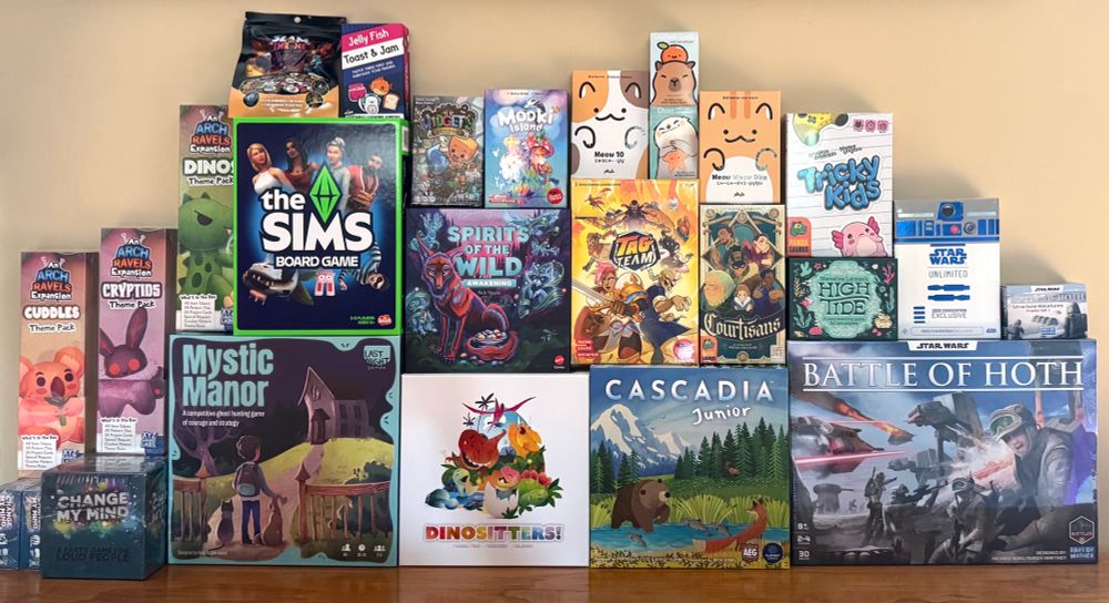 A pile of board games! List of games included: 

Kickstarter Pick-Ups: Arch Ravels expansions (Magic Socks not pictured), Widget’s Workshop

Purchased: Mystic Manor, Dinositters, Battle of Hoth, Spirits of the Wild - Awakening, High Tide, Star Wars Unlimited 2025 Convention Exclusive, Jelly Fish Toast & Jam, Meow 10, Capybara Crush, Otter, Meow Meow Dice

Gifted/Demo/Content Creator/Event Perk: Change My Mind, Cascadia Jr., The Sims Board Game, Tag Team, Courtisans, Slam Throne, Mooki Island, Tricky Kids