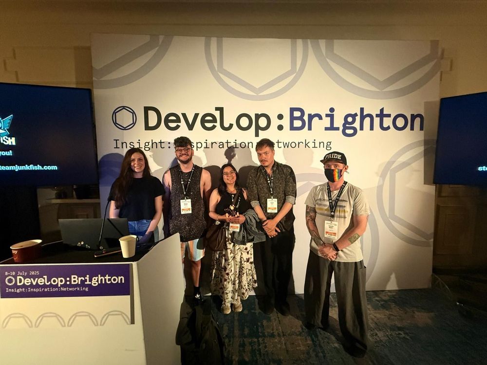 A group of five individuals posing in front of a "Develop: Brighton" backdrop, showcasing a networking event atmosphere.
