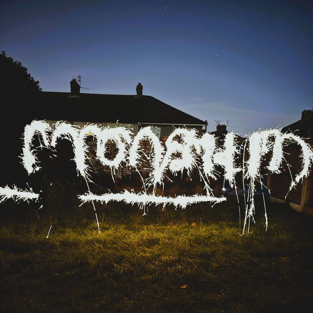 A dark backyard scene with illuminated text written by using a sparkler, spelling "MONSTRUM" against a twilight sky.