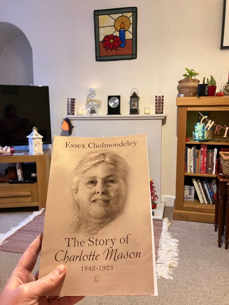 A copy of the Story of Charlotte Mason held in a left hand by a white person. 