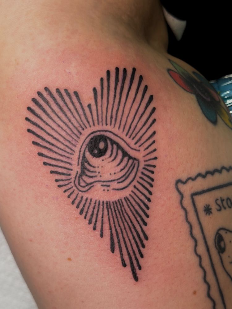 Black line work tattoo of an eye surrounded by lines going away from it in the shape of a heart 