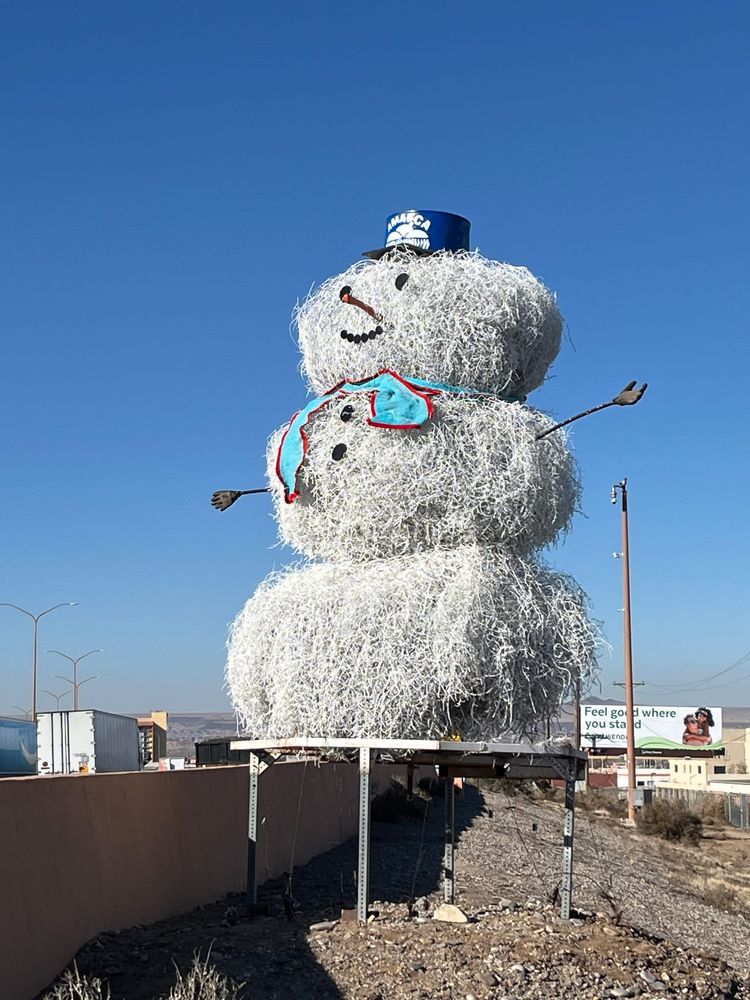 Big white snowman made of tumbleweeds shown against a marvelously blue New Mexican sky. 