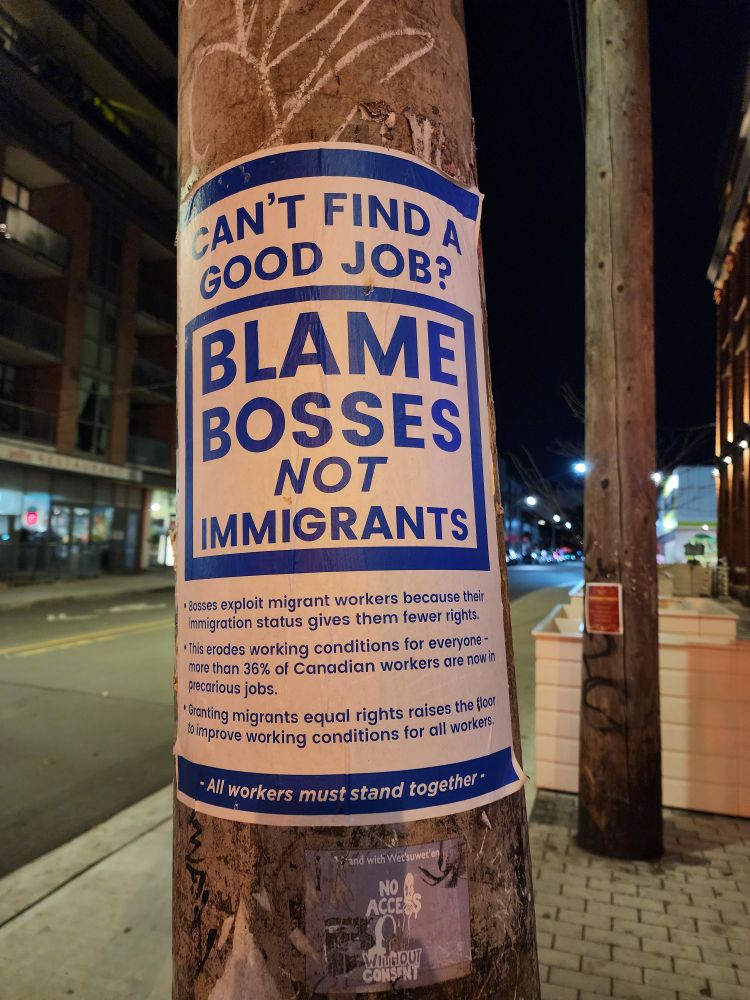 Sign pasted to a pole in Toronto says "Can't find a good job? BLAME BOSSES NOT IMMIGRANTS"
