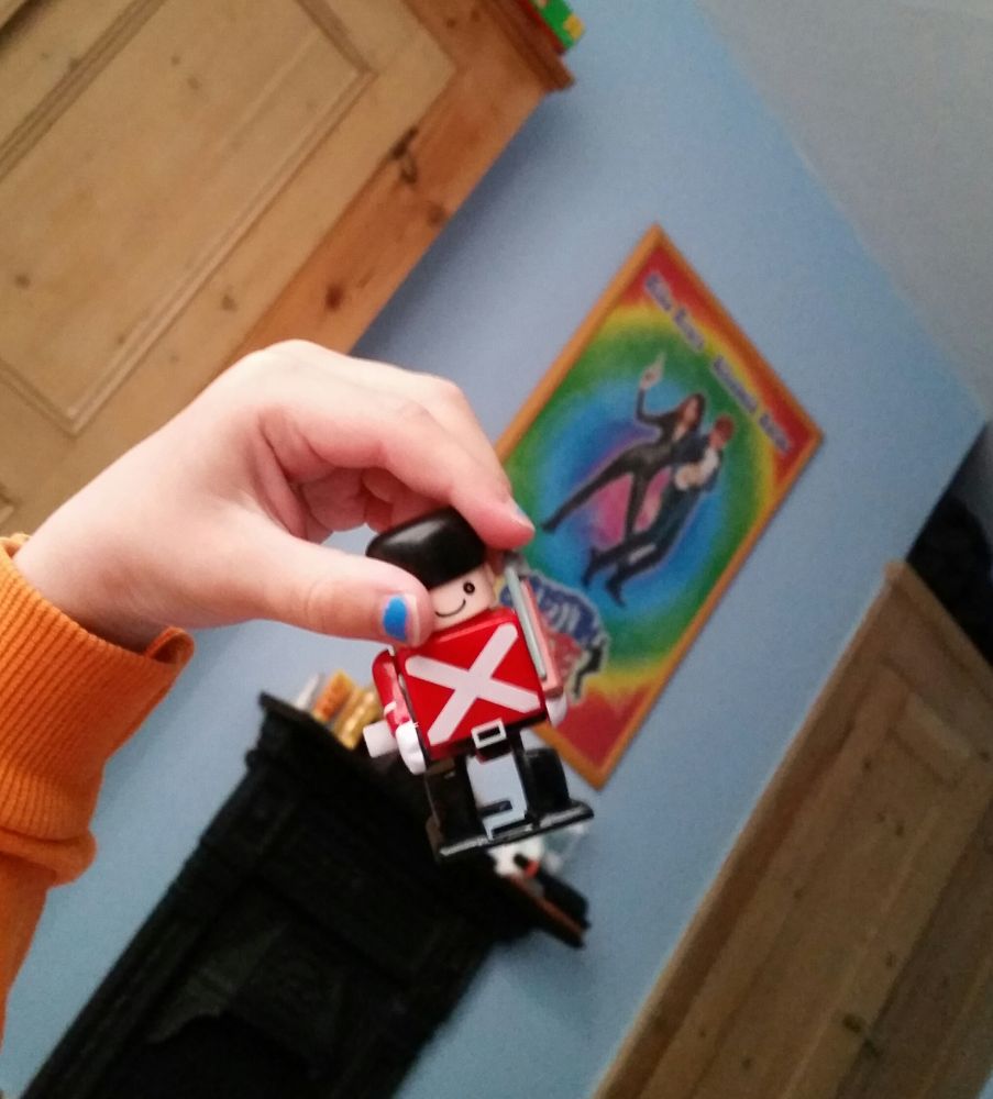 A child's hand holding a small plastic wind up soldier toy 