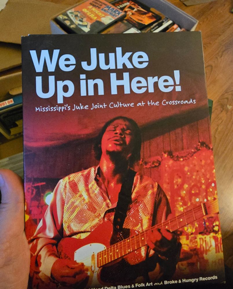 A hand holds the DVD box for "We Juke Up in Here! Mississippi's Juke Joint Culture at the Crossroads".