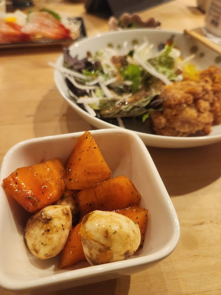 柿とモッツァレラチーズを塩コショウオリーブオイルとバルサミコで合えたものが小鉢に入っている。奥にはお総菜の唐揚げと甘エビのお刺身。